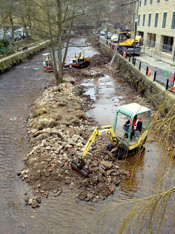 Diggers in the river dredging out debris and sediment following flooding